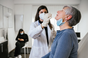 Healthcare worker performs nose swab adult woman in the clinic - Doctor takes sample with tester from the patient to check if positive for Coronavirus Covid-19 infections during pandemic - Copy space