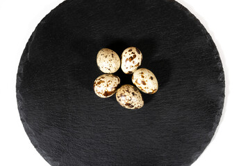 Boiled spotted quail eggs  on black stone plate , isolated on white background. Healthy Food Products Concept.