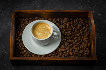 Cup of black coffee and roasted coffee beans in a wooden box