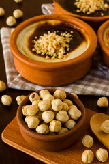Traditional Turkish Luxury size hazelnuts in wooden bowl in front of blurred rice pudding,vertical image
