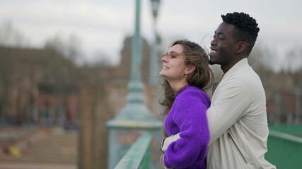 Fototapeta premium Happy millennial interracial couple standing outside laughing and smiling
