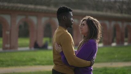 Interracial couple empathic embrace. Young woman romantic connection with partner outside