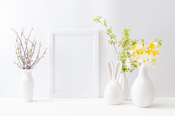 Home interior with easter decor. Mockup with a white frame and spring flowers in a vase on a light background