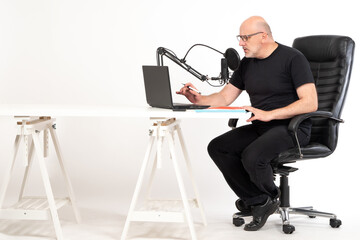 The concept of a radio host, streamer and blogger. A man sits in a chair and writes down his speech...