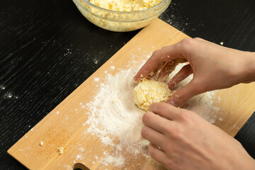 Women's hands form, sculpt cottage cheese pancakes on a wooden plank close-up, photo from behind