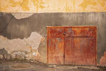 old rusty door with a padlock, fragment of a terracotta iron door with a lock, cracked paint on metal