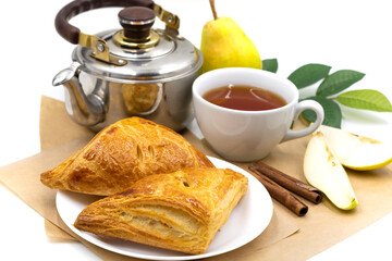 Puff pastry with pears. Composition with a cup of tea and a kettle.