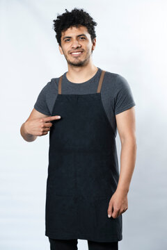 Black apron mockup - Hispanic young man pointing at apron smiling on white background - young worker - template for text on clothes