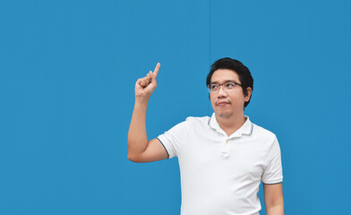 Asian man Pointing finger on wall blue color background  - 417925066