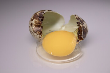 broken Quail egg isolated on white background with leaking white and yolk. healthy raw food