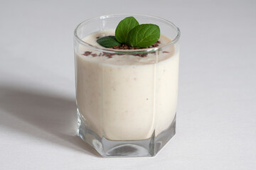 A glass of banana smoothie with mint and flax seeds.