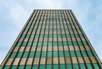 Modern facade with green windows and dramatic sky