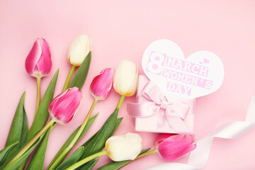 Tulip flowers, card in shape of heart with text 8 March Womens Day and gift box on pink background