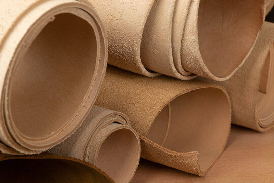 Vegetable tanned leather rolls on a leather workshop desk. Different colors of leather