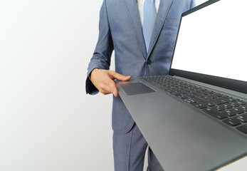 Caucasian businessman with a laptop showing the blank screen and pointing.