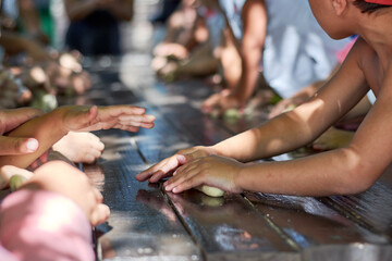 A close up of child's hands kneading dough. Group of children kneading dough while learning how to make bread in a farm.