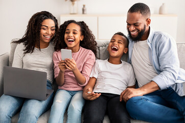 Happy african american family holding and using gadgets