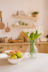 Bouquet of spring flowers in a vase and fruit on the kitchen table. Scandinavian style. Mothers Day. March 8, International Women's Day