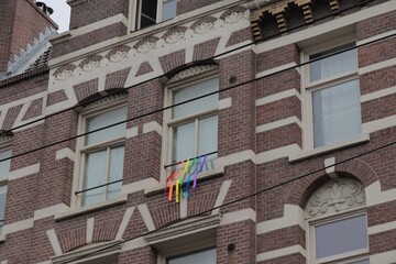Rainbow Colored Ribbons Hanging from a Window of a Brown and White Brick Building During Amsterdam Pride 2018
