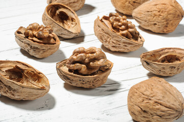 Walnut kernels and nuts in shell on white wooden table