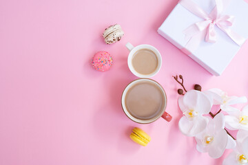 Obraz na płótnie Canvas Women day 8 March concept. Morning coffee, macarons and white orchid flowers on pink pastel background. Flat lay. orkide