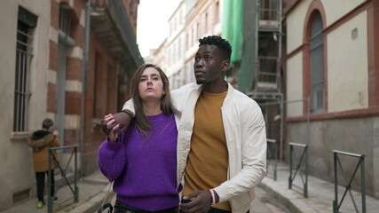 Young interracial couple walking together, modern millennial boyfriend and girlfriend in street