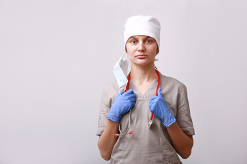 Portrait of female doctor in medical uniform and removed mask from the face. Stethoscope on the neck. on white background. Healthcare And Medicine. Disease prevention concept.