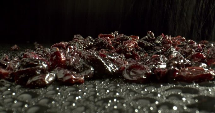 Pouring water over raisins. Raisins close-up. Macro shot of raisins on wet black surface. Sulfur dioxide treated raisins. High quality.