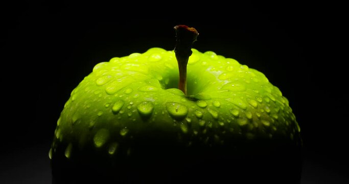 A green apple close up, rotating on a black background