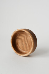 A small round wooden bowl on a white background. Wooden dishes with their own hands.