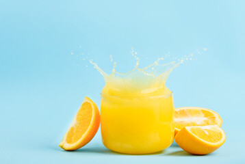 Glass of fresh orange juice on a blue background. Splash. Copy space 