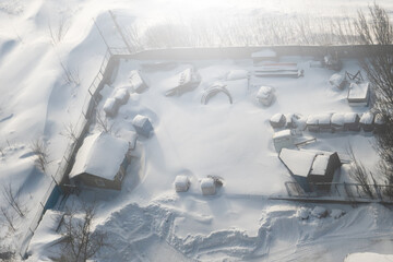 Snow covered village workshop and a pile of junk. Top view.