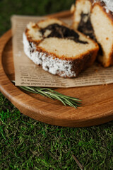 Delicious sweet strudel on a wooden plate. Roll sprinkled with powdered sugar on baking paper.