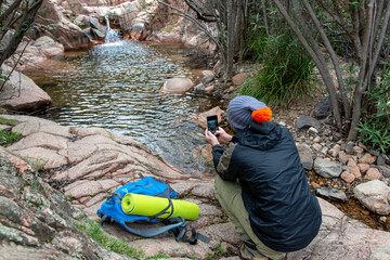 trekker resting near a river and takes pictures