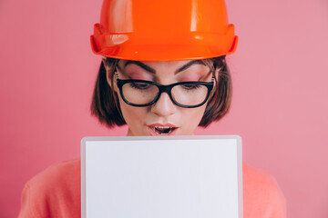 Pretty amazed surprised woman worker builder hold white sign board blank against pink background. Building helmet.