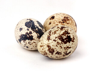 three quail eggs on a white