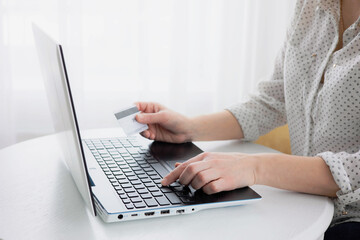Woman's hands holding credit bank card and using laptop computer at home Online shopping concept