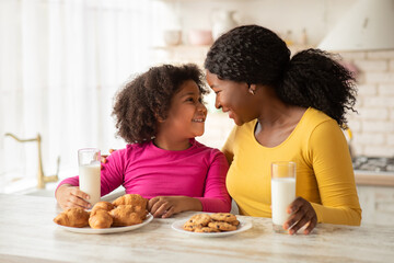 Happy Black Mother And Daughter Bonding Together While Having Snacks In Kitchen