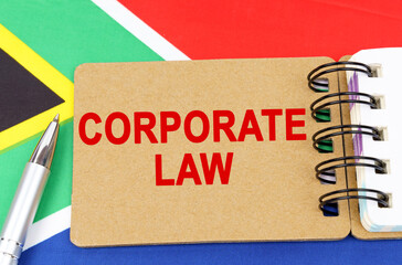 Against the background of the flag of South Africa lies a notebook with the inscription - CORPORATE LAW