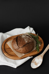 Freshly baked round bread on baking paper on a dark background. Freshly baked bread and white flour.
