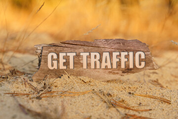 On the sand against a background of yellow grass a plate with the inscription - GET TRAFFIC