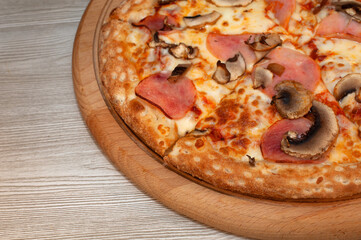 Pizza with ham, mushrooms and cheese on a board