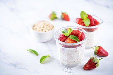 Oatmeal porridge with milk and fresh strawberries in a glass