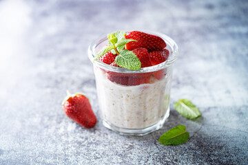 Oatmeal porridge with milk and fresh strawberries in a glass