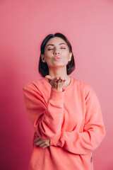 Woman wearing casual sweater on background smiling looking at the camera blowing a kiss with hand on air being lovely