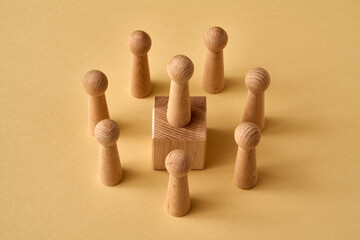 One wooden figure standing on a cube higher than others - concept of leadership or hierarchy