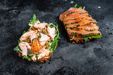 Sandwich toast with smoked salmon, arugula and cream cheese. Black background. Top view