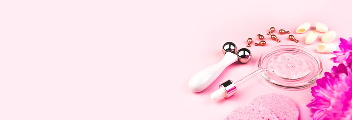 Skincare home spa. Beauty accessories on pink background banner. Cosmetic, feminine face massager