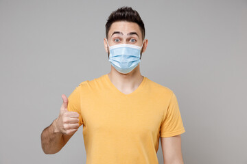 Young caucasian happy man 20s in yellow basic t-shirt in sterile face mask to safe coronavirus...