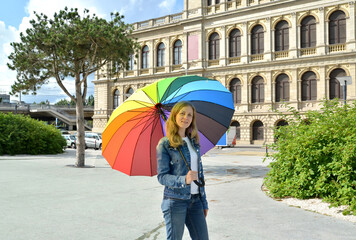 A young woman under a rainbow umbrella against the background of an exchange building. Kaliningrad